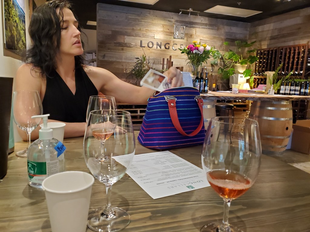 A photo of a woman with wine glasses in front of her.